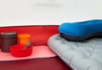 Inside a tent with inflatable pillow, cookware, and sleeping pad, ideal for camping.