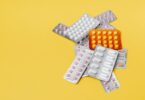 Various pills in blister packs on a yellow background, ideal for health-related themes.