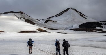 Three hikers traverse snowy peaks in Iceland, capturing the essence of adventure and winter exploration.