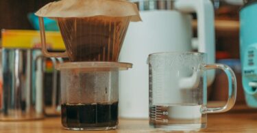 Close-up of a pour over coffee setup with water in a glass, emphasizing home brewing methods.