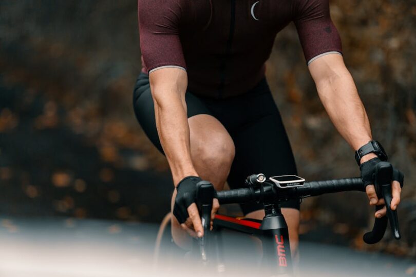 Detailed shot of a cyclist wearing sportswear and gloves riding a road bike outdoors.